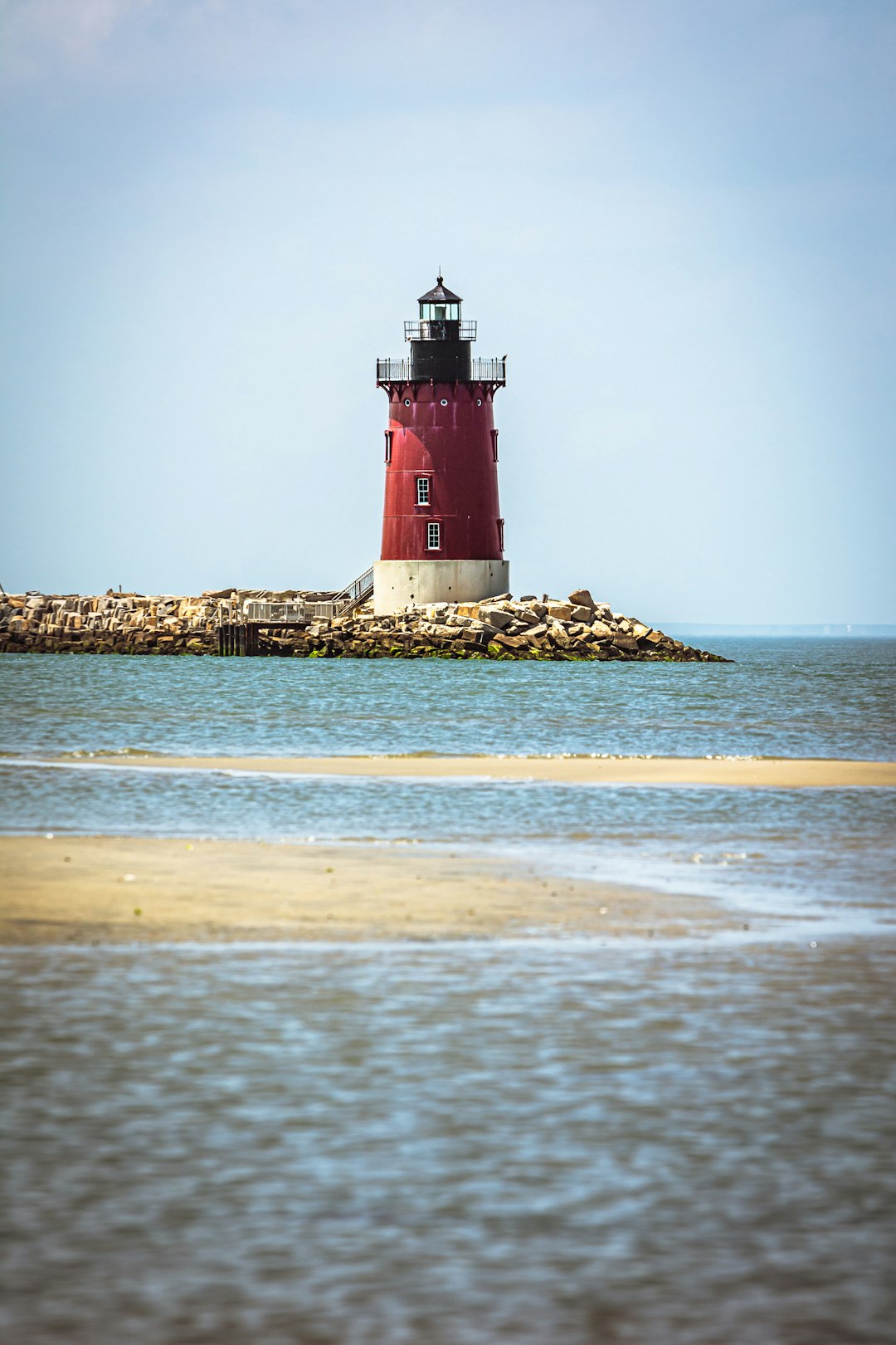 A red and white light house sitting on top of a small island
