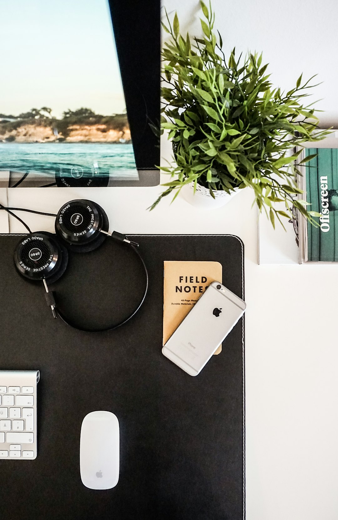 Flatlay with a small notebook by Spanish Scholar black headphones beside space gray iPhone on brown table