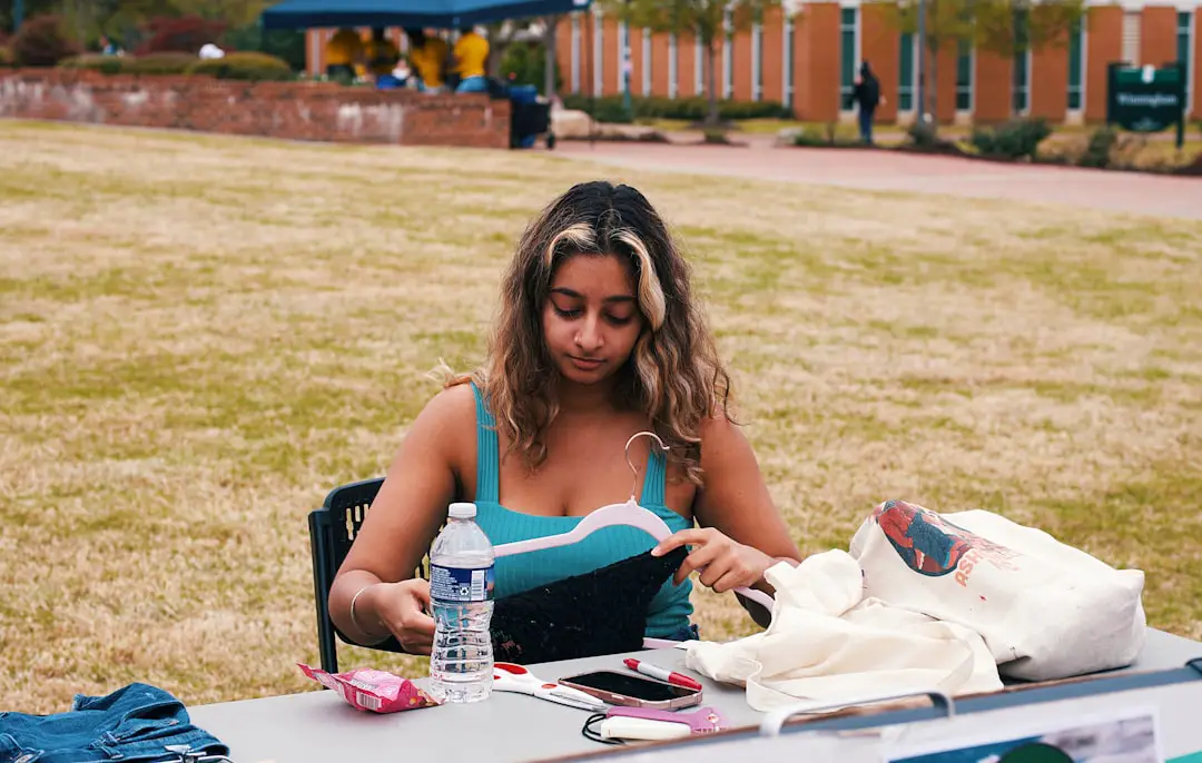 A woman sorts through clothes at an outdoor table.